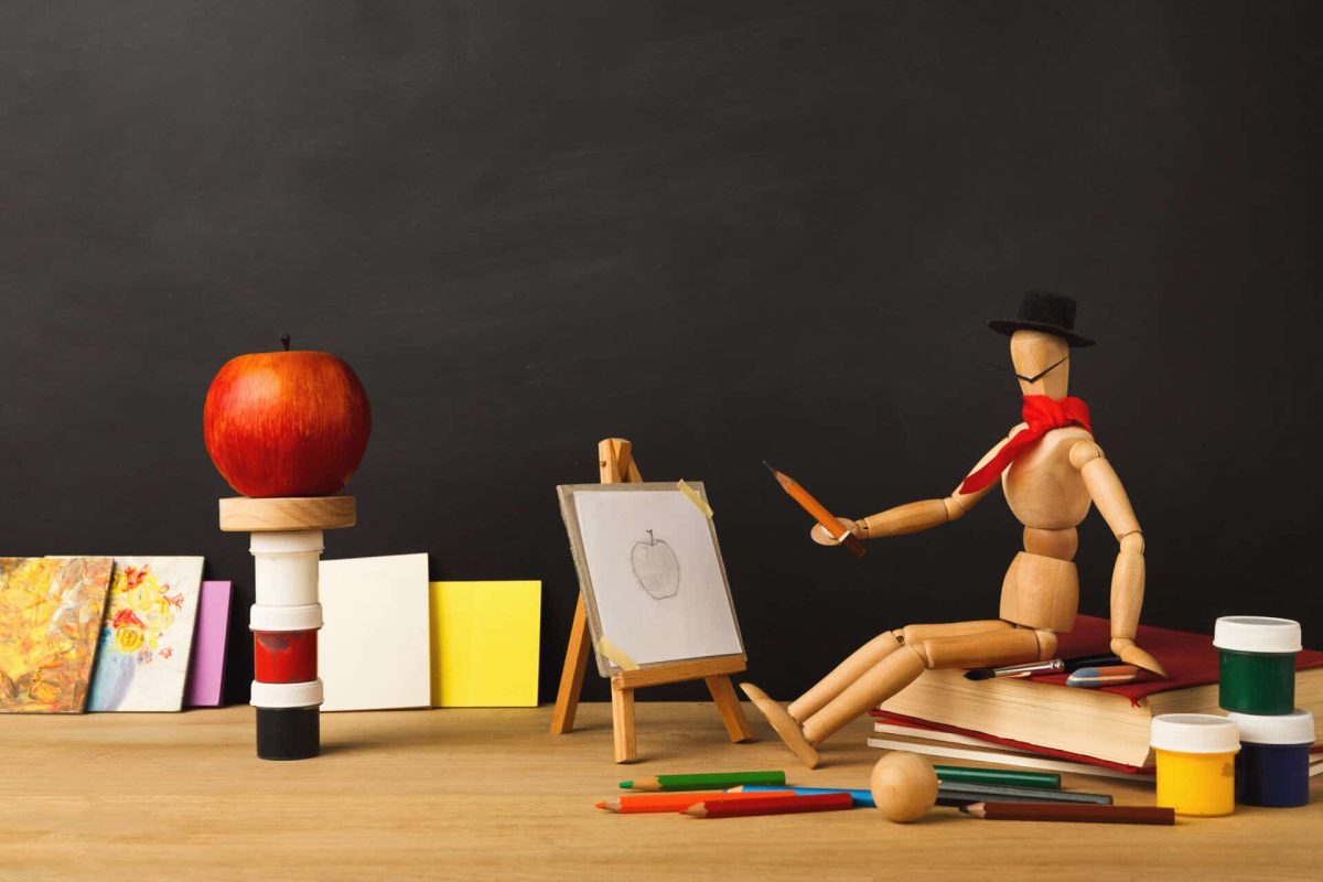 Back to school conceptual background Art background. Wooden marionette artist in hat sitting on old book and drawing an apple against empty classroom blackboard, copy space. Back to school concept
